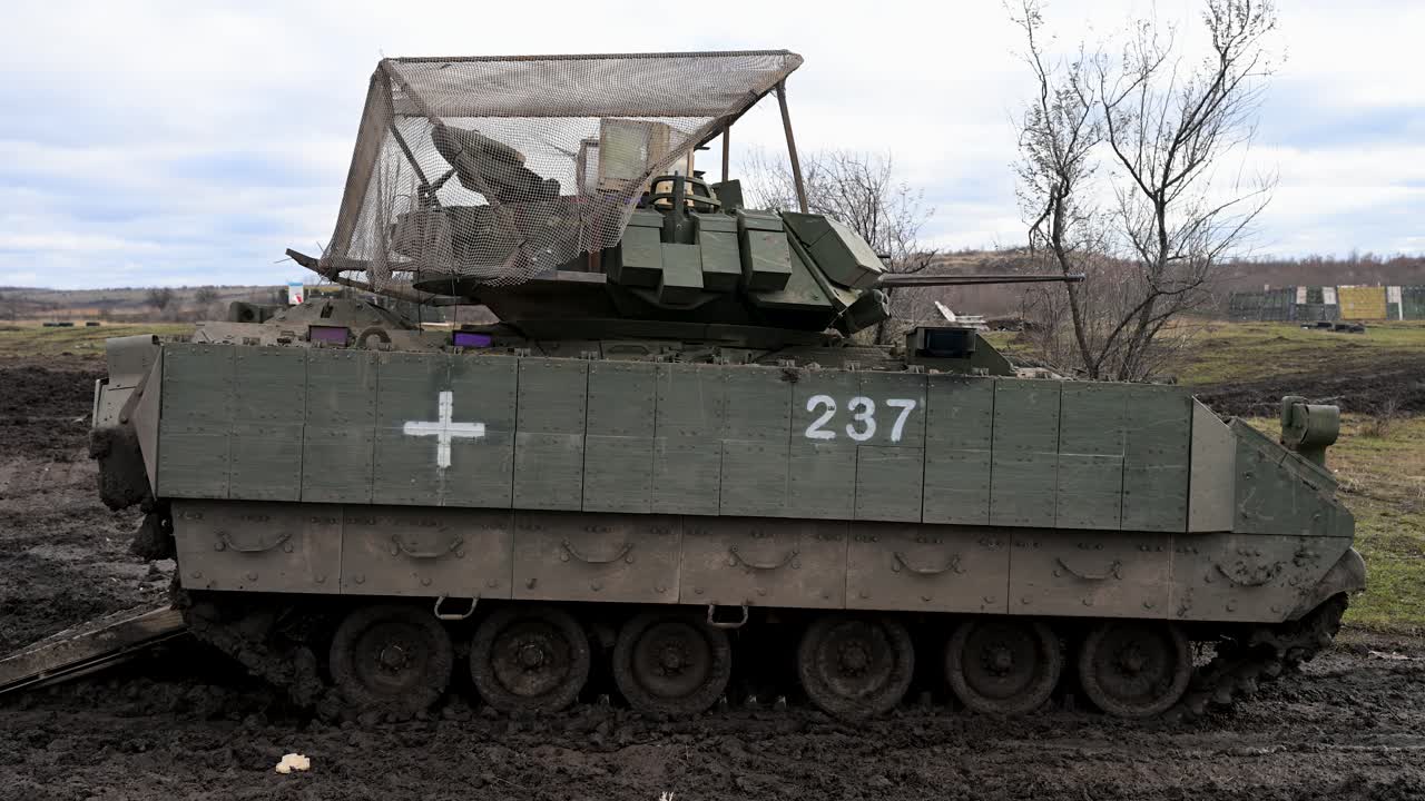 A heavily modified M2 Bradley IFV, adapted for survival on the Ukrainian front. A medical cross and anti-drone cage are key modifications for this modern battlefield