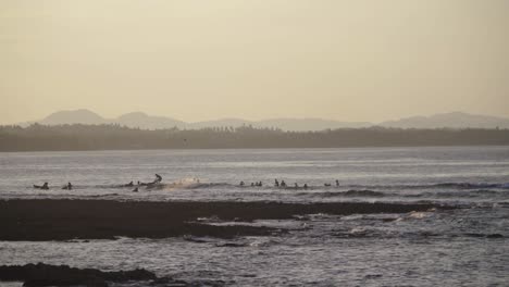 Surfistas-Montando-Olas-Con-Montañas-Al-Fondo