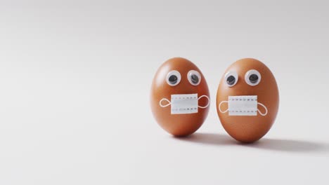 video of eggs with eyes and face masks on a white surface