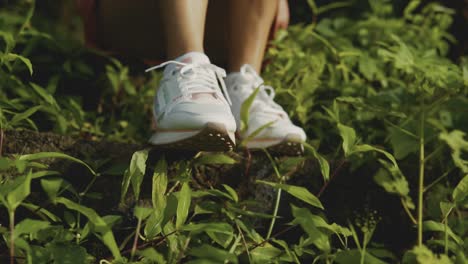 A-woman-sits-outdoors-on-the-wild-grass-with-white-shoes-during-the-daytime