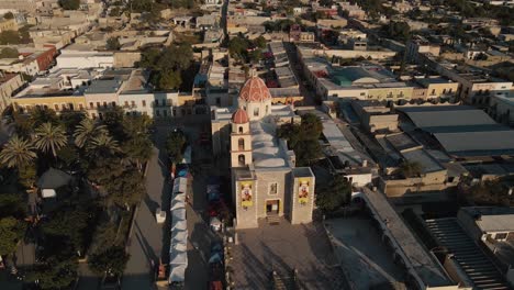 aerial view of a church next to a square with palm trees in a peaceful mexican town at dawn