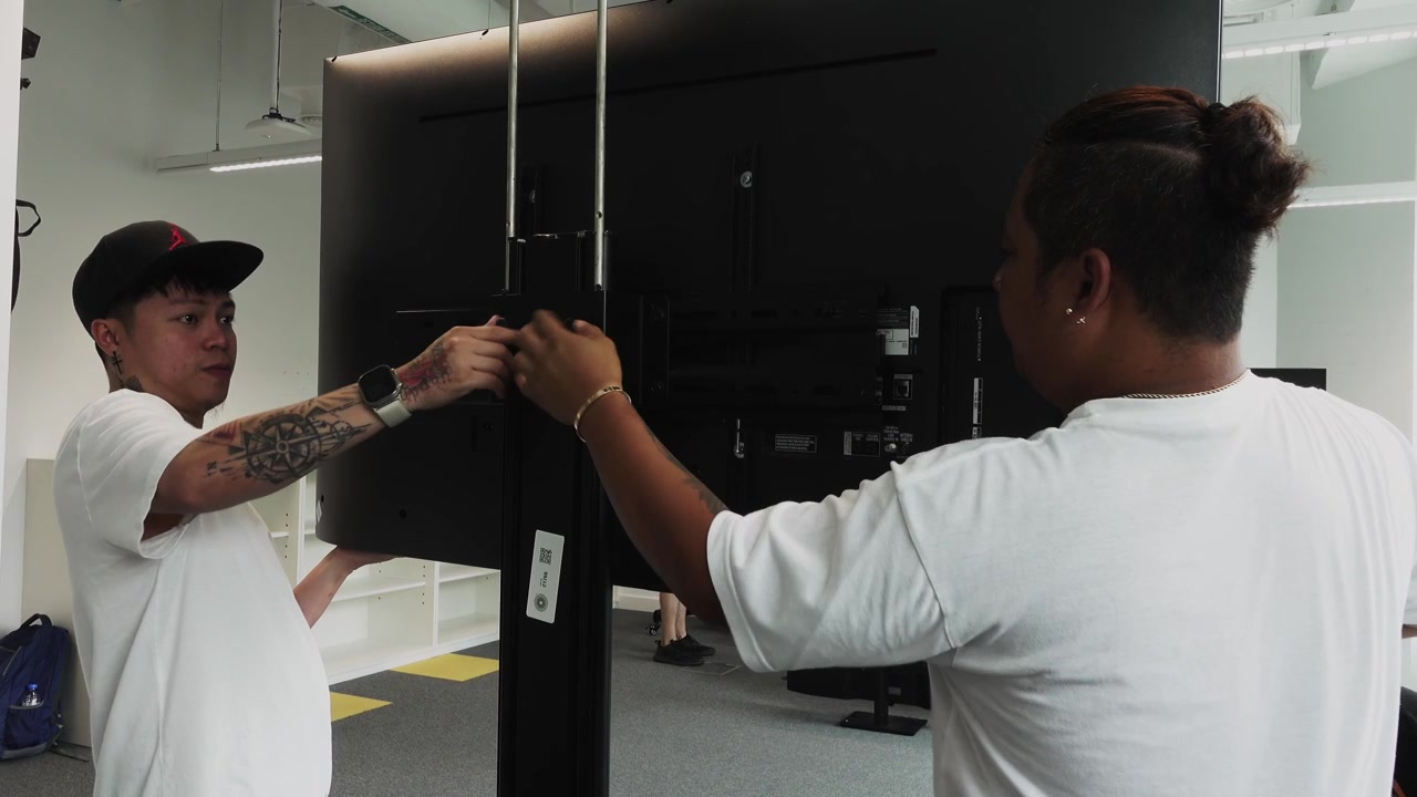 Men setting up a TV monitor on a stand for a show