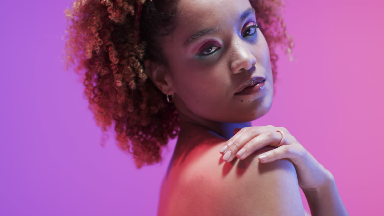 Biracial woman with dark hair in blue and pink light with copy space, slow motion