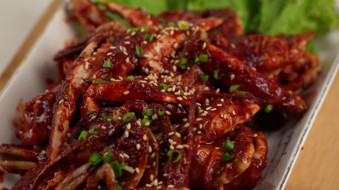 Fresh raw crab coated in a spicy, savory sauce, topped with sesame and scallions. 신선한 꽃게에 매콤한 양념이 어우러진 감칠맛 가득한 한 접시.