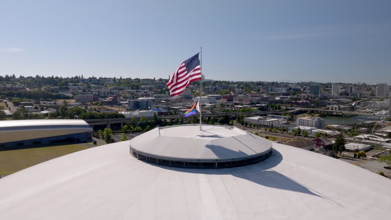 American Flag And Pride Flag Flying Over The Tacoma Dome In Tacoma, Washington, USA. - aerial shot