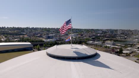 american flag and pride flag flying over the tacoma dome in tacoma, washington, usa. - aerial shot