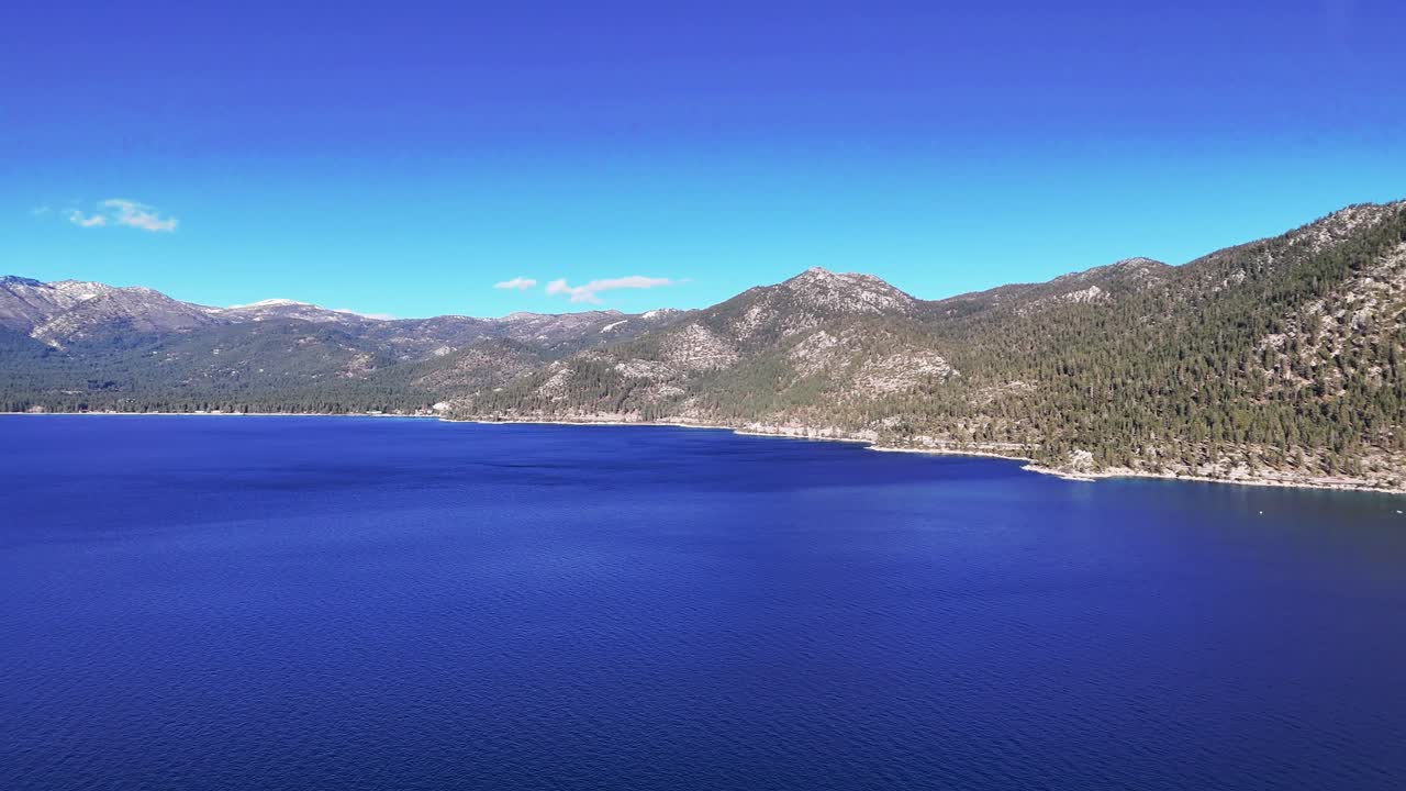 Aerial view of deep blue water at Sand Harbor State Park in Lake Tahoe Nevada with pine covered mountains and clear blue sky on a sunny day