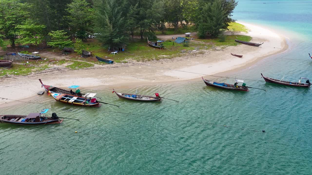 Drone captures longtail boats along Sarasin Beach in Phuket, Thailand. Clear waters and sandy shores create a tranquil scene