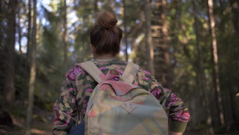 young woman with a bag walks in a forest with brown hair and blurry background in slow motion