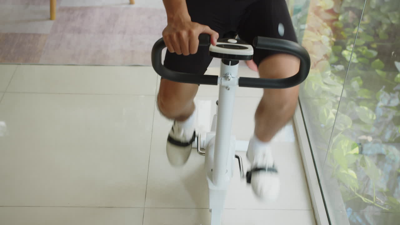 Man Working out on Fitness Bike and Talking to Wife Wiping Dust