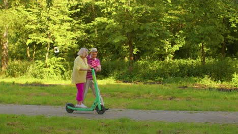 senior old stylish tourists grandmother, grandfather using electric scooter enjoying learning ride