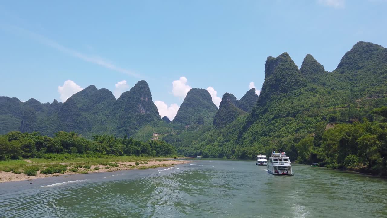 Thuyền du lịch chở khách di chuyển giữa cảnh quan núi đá vôi trên sông Li hùng vĩ từ Quế Lâm đến Dương Sóc.
