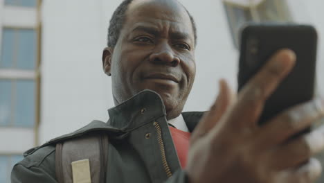 mature man's changing expressions while using a smartphone outdoors