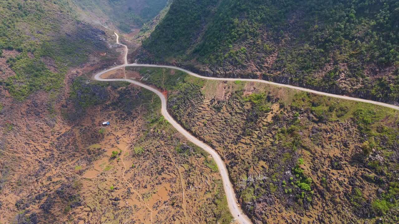 A breathtaking aerial perspective of Ha Giang's serpentine roads, showcasing motorcycles navigating through dramatic landscapes of rice fields and mountains.