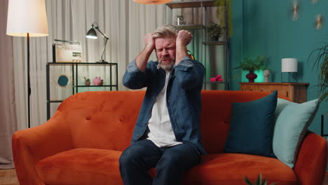 a man sitting on a couch looking frustrated and tired