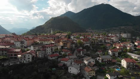 Un-Buen-Clip-De-Dron-Aéreo-Inclinado-Sobre-El-Pueblo-De-Tolmin-Slowenia-En-Las-Montañas-Triglav-Con-Destello-De-Lente-Rosa