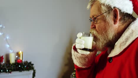 santa claus relajándose en una silla y tomando leche