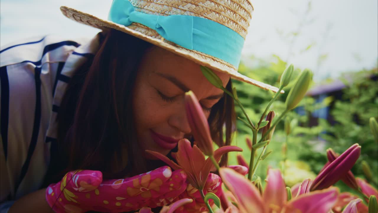 Woman with straw hat tending to vibrant flowers in a lush garden, showcasing nature's beauty
