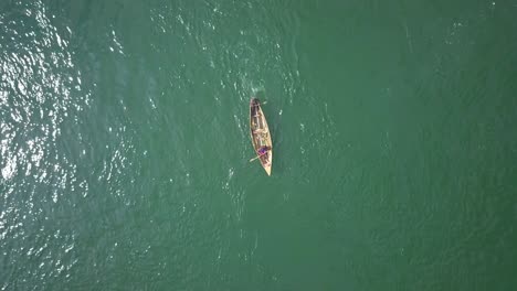 aerial top down view of fishermen rowing a small wooden boat on the river nile in uganda, africa, showcasing the vastness of the river and traditional fishing practices
