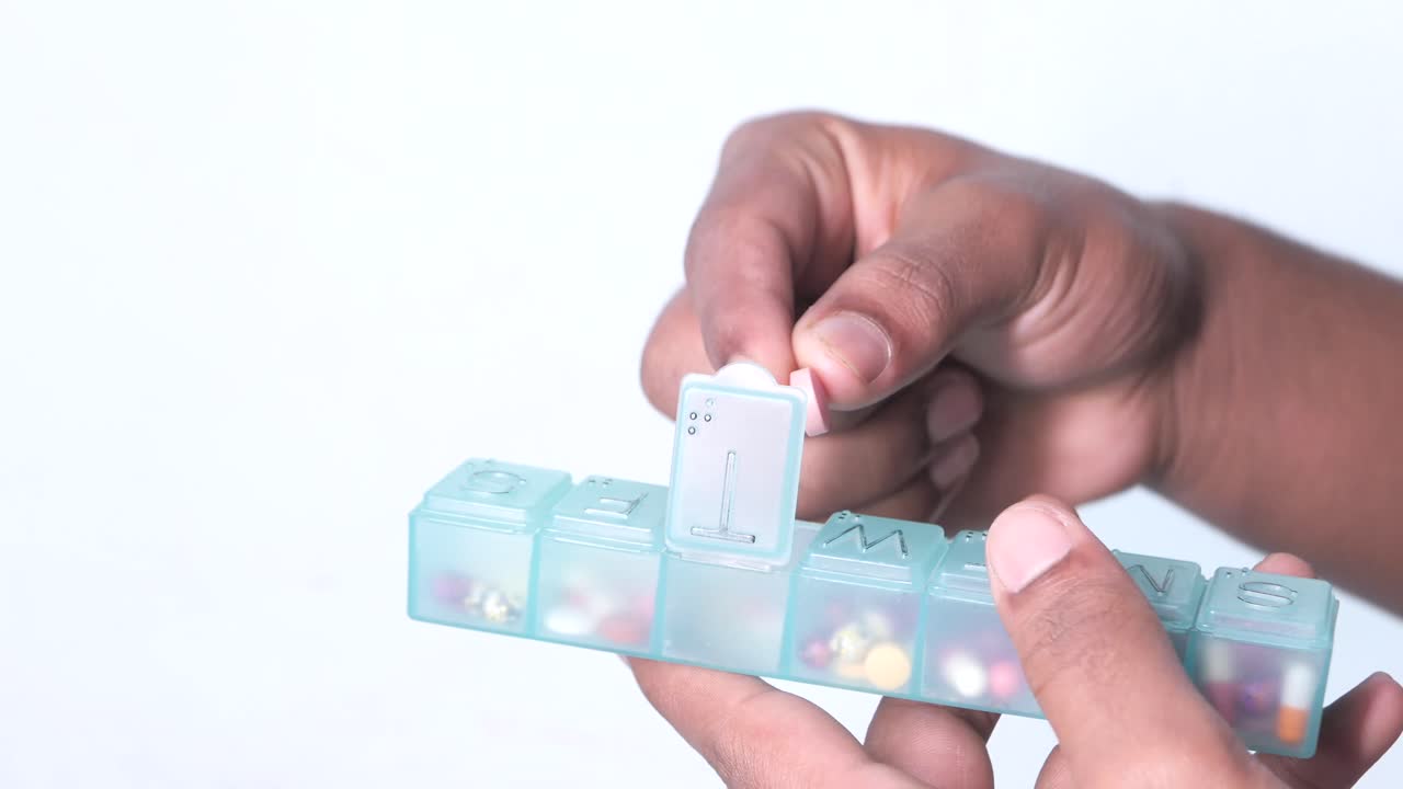 persona que abre un organizador de pastillas diarias