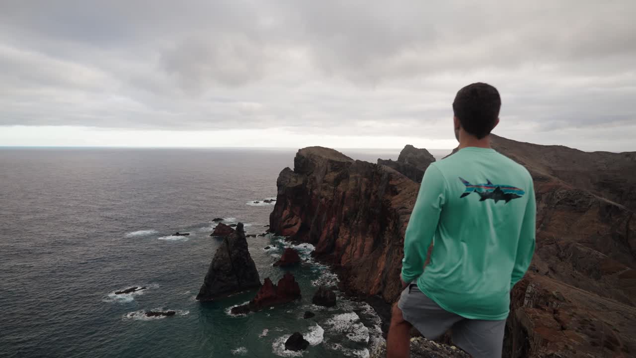 A man gazes at the dramatic coastline and sharp cliffs of Ponta de São Lourenço in Madeira, Portugal.