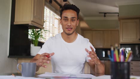 happy latin man gesturing and having video call in kitchen