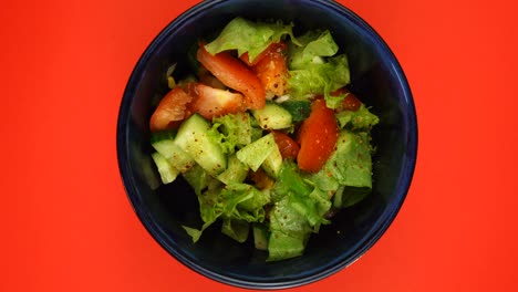 cucumber tomato lettuce leaves salad with paprika fast rotating on a red background