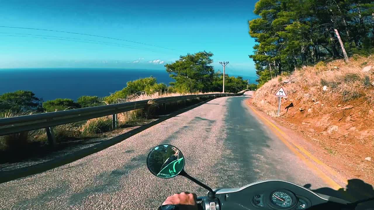 conduciendo una moto en una carretera escénica en la montaña con vistas al mar - kabak, turquía
