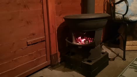 calentador de estufa de leña de hierro fundido ardiendo en cocina de cabaña de madera al aire libre