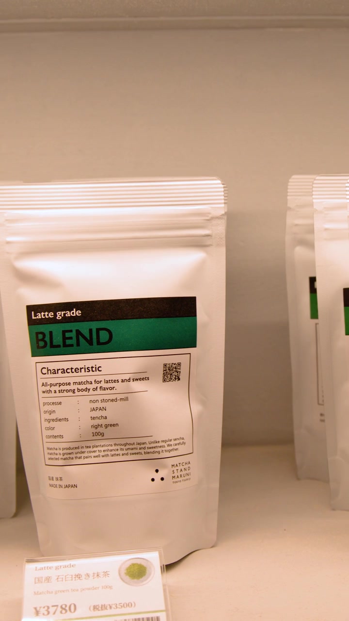 Close-up panning shot of white bags containing premium matcha green tea on a shelf.