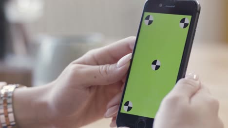 mujer sosteniendo un teléfono inteligente con una pantalla verde y puntos de calibración