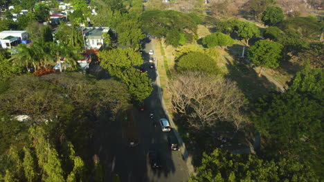 Aerial-view-following-cars-in-the-Manila-memorial-park,-in-the-sunny-Philippines