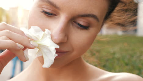 woman smelling a white flower