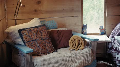 cozy chair with rustic wooden walls, colorful pillows, and natural light, symbolizing tranquility and warmth.
