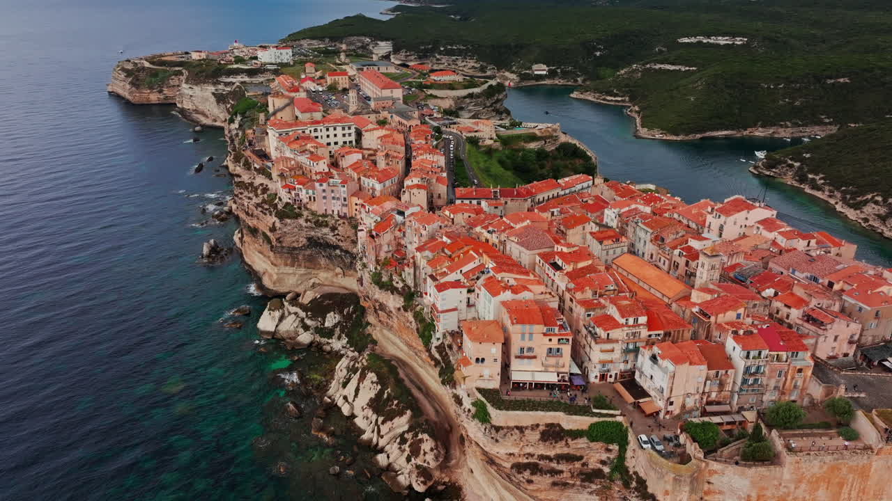 Aerial drone shot over the historic coastal town of Bonifacio in Corsica, France. High view of the rocky steep cliff and the turquoise sea. Ancient Citadel overlooking the rugged coastline