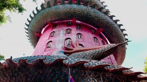 looking up at the wat samphran temple with a dragon coiled around the outside of the red temple in amhoe sam phran province thailand