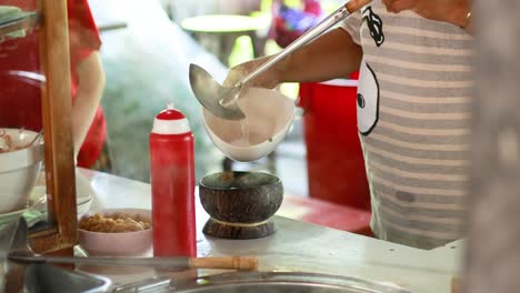 el vendedor sirve sopa de fideos en la cáscara de coco