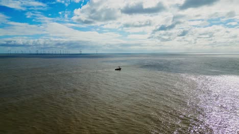 Distant-fishing-boat,-trawler-off-the-East-Coast-of-the-UK,-sailing-into-the-sun-on-a-choppy-sea