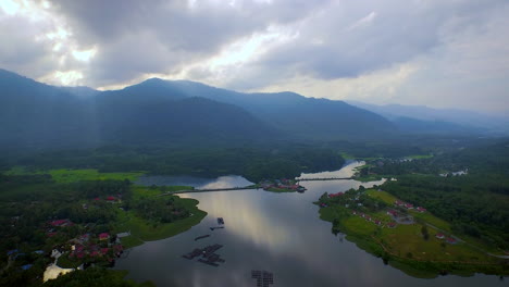 Toma-Aérea-Del-Lago-Raban-Con-Montaña,-Piscifactoría-Y-Bosque-Durante-La-Hermosa-Puesta-De-Sol-Con-Dios-Ray,-Malasia