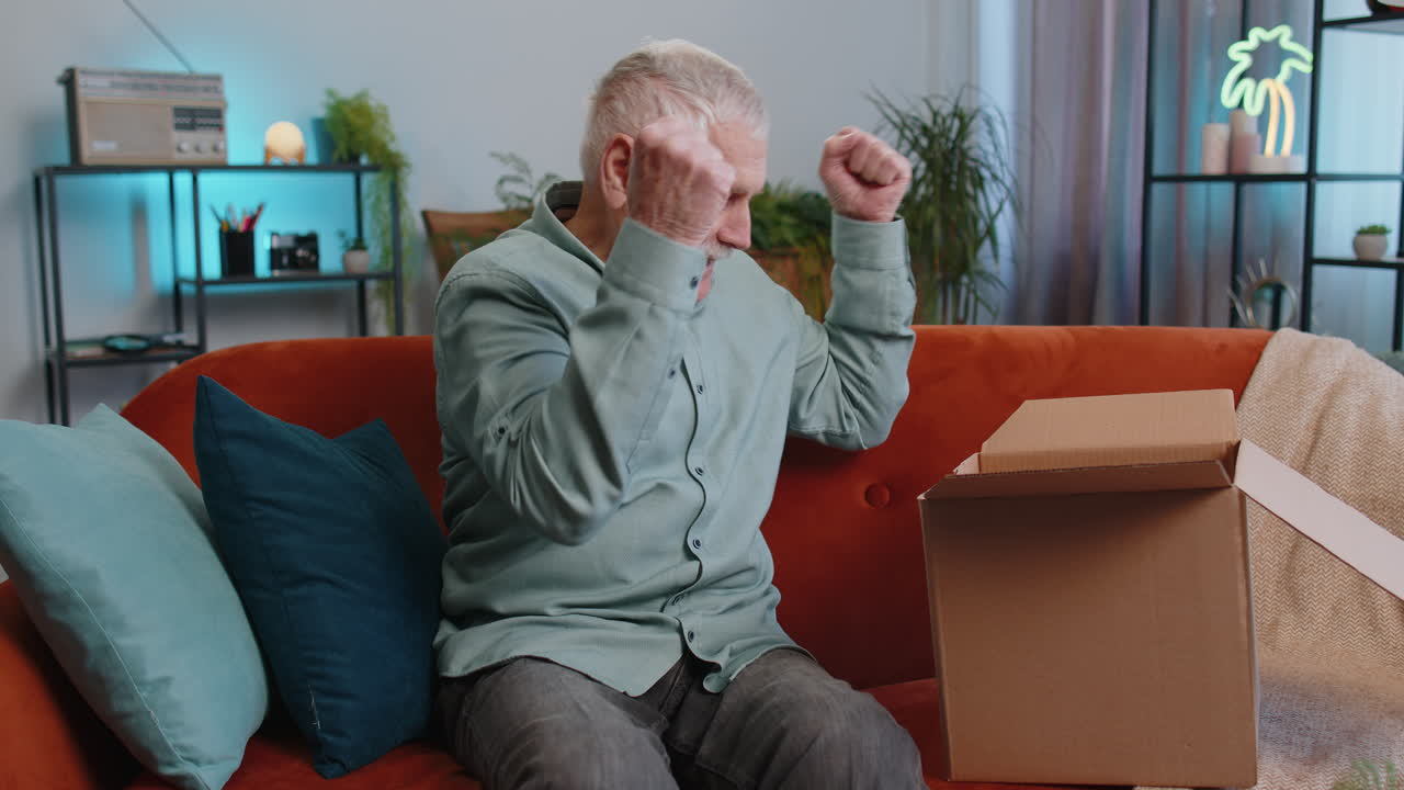 Grandfather man shopper unpacking cardboard box delivery parcel online shopping purchase at home