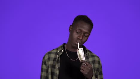 un hombre serio con ropa casual está encendiendo su cigarrillo con un billete de un dólar. concepto idea de riqueza, hombres ricos. aislado sobre fondo azul