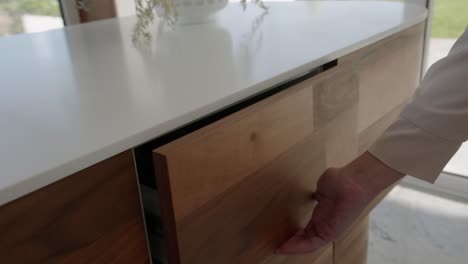 woman opens cutlery drawer wooden cabinet with white worktop