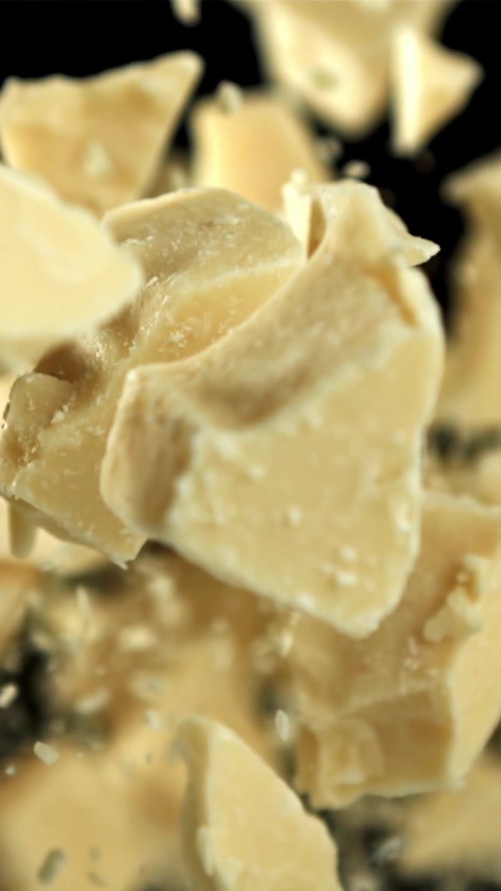 Pezzi di cioccolato bianco che cadono al rallentatore su sfondo nero