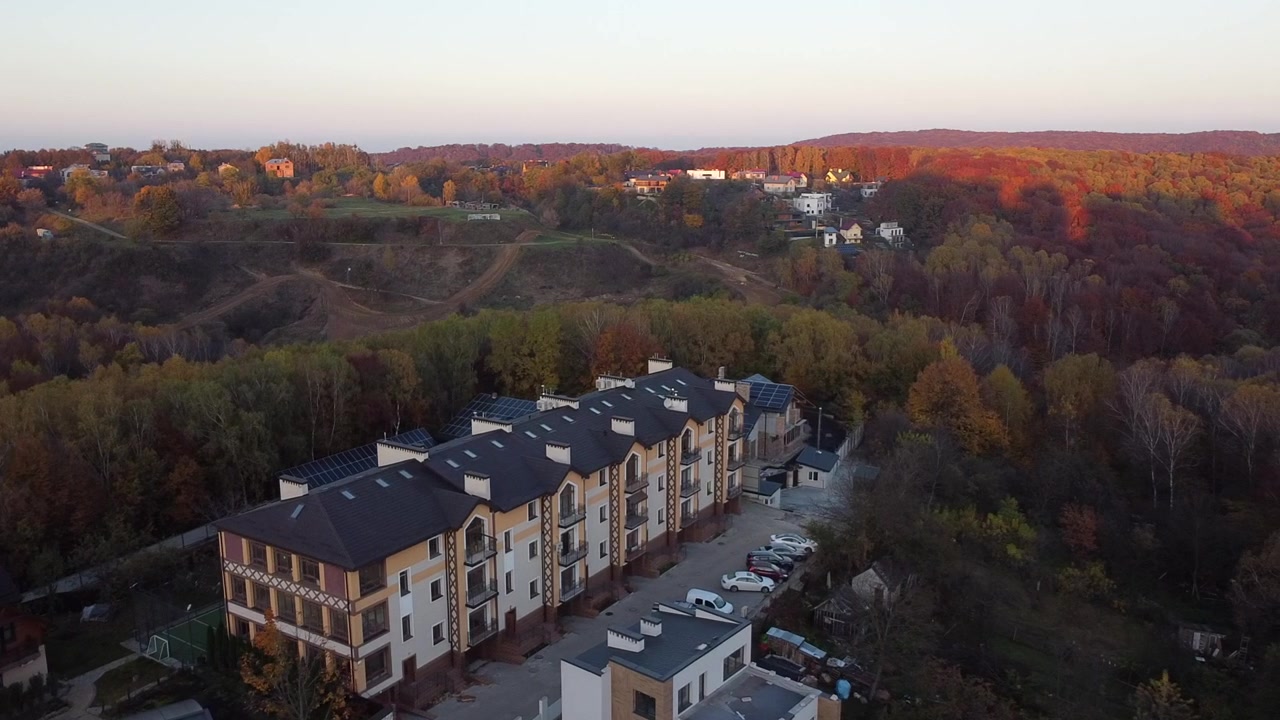 Apartman binasının ve ormanın üzerinden uçan bir dronun havadan görünümü