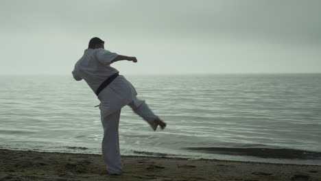 bearded sportsman practicing attack on sunset outdoor. karate man learning kicks