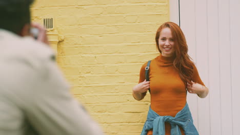 woman posing and man taking photos on camera as young couple travel through city together