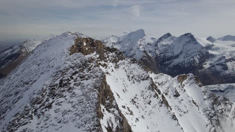 Aerial-flight-towards-summit-cross-and-idyllic-lakes-in-the-valley---Austrian-snowy-Alps-in-winter