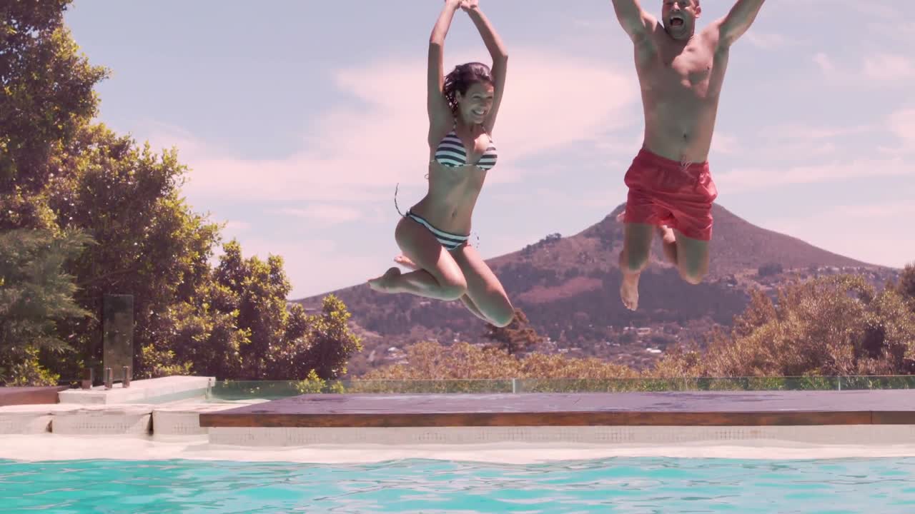 Coppia felice che salta in piscina