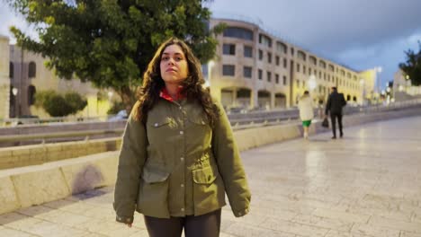 a woman is walking down a sidewalk in a city