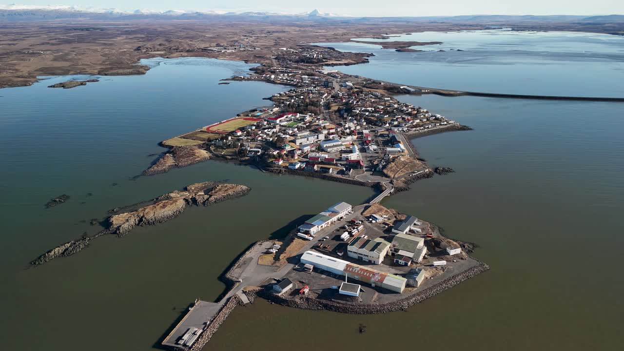 Aerial drone video overlooking the small western town of Borgarnes, Iceland, surrounded by water on a clear sunny day in the land of fire and ice